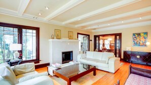 A spacious living room with a fireplace, white sofas, and a coffee table.