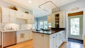 A modern kitchen with white cabinetry, a central island, and a large window providing natural light.