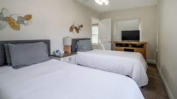 A bedroom with two beds, a ceiling fan, a TV, and decorative wall art.