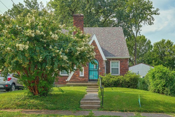A two-story house with a brick chimney, a blue door, and a small front porch.
