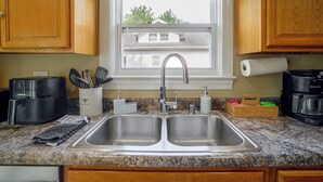 A kitchen with a double sink, a coffee maker, and a window with a view of buildings. - Near Churchill Downs: Pet Friendly, Fenced Yard! (Louisville)