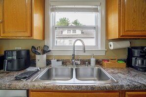 A kitchen with a double sink, a coffee maker, and a window with a view of buildings. - Near Churchill Downs: Pet Friendly, Fenced Yard! (Louisville)
