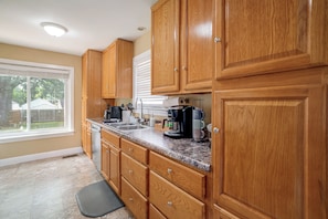 A kitchen with wooden cabinets, a stainless steel sink, and a coffee maker. - Near Churchill Downs: Pet Friendly, Fenced Yard! (Louisville)