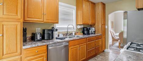 A kitchen with wooden cabinets, a stainless steel dishwasher, a granite countertop, and a gas stove.