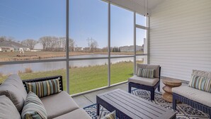 Een zonnige kamer met grote ramen met uitzicht op een rivier, ingericht met banken en een salontafel.
