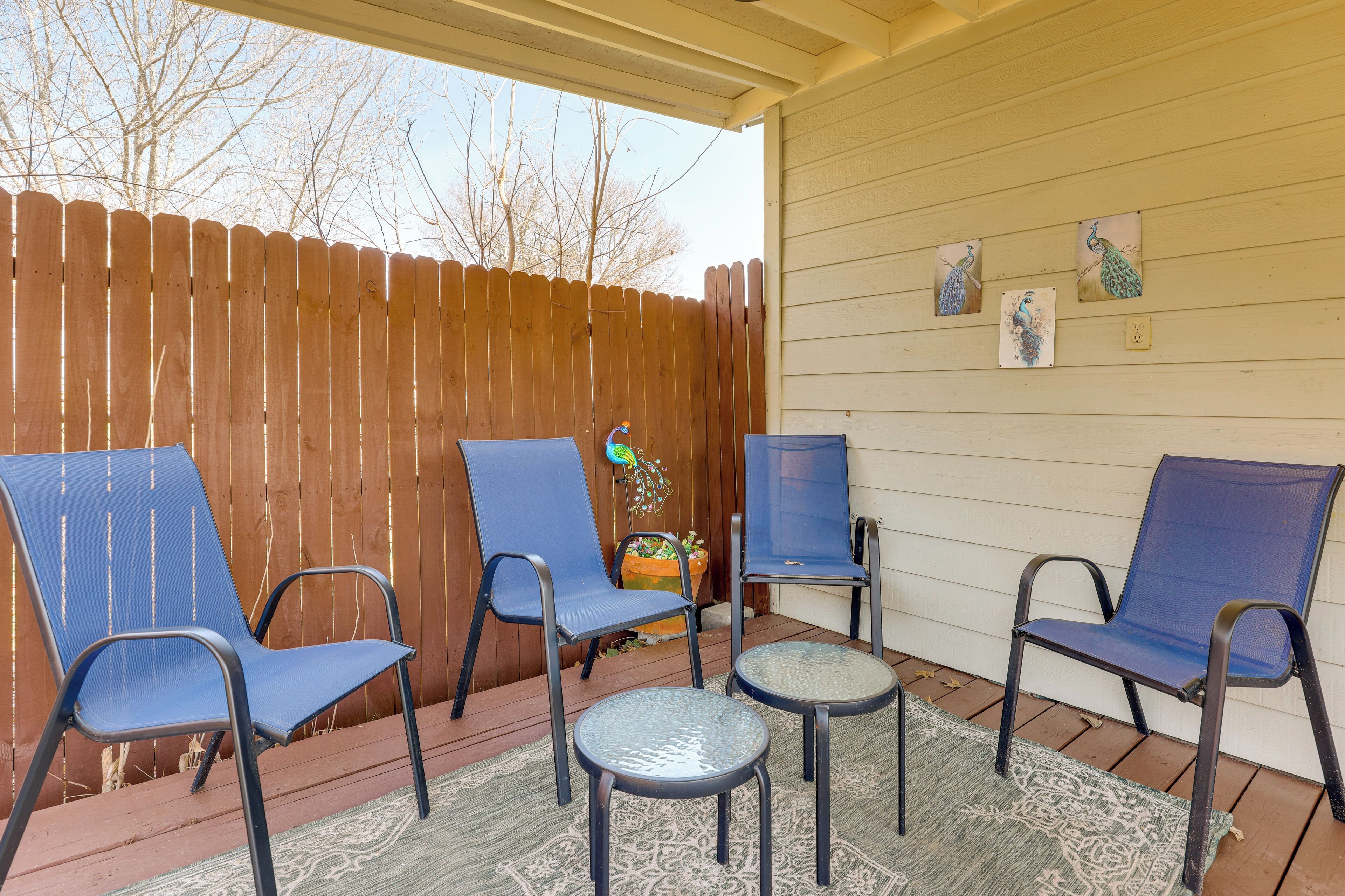 A covered patio area with four blue chairs and two small round tables.