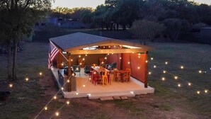 A covered outdoor patio with a dining table and chairs, surrounded by string lights.