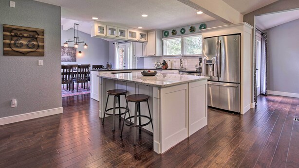 A modern kitchen with a central island, stainless steel appliances, and a dining area with a wooden table and chairs.
