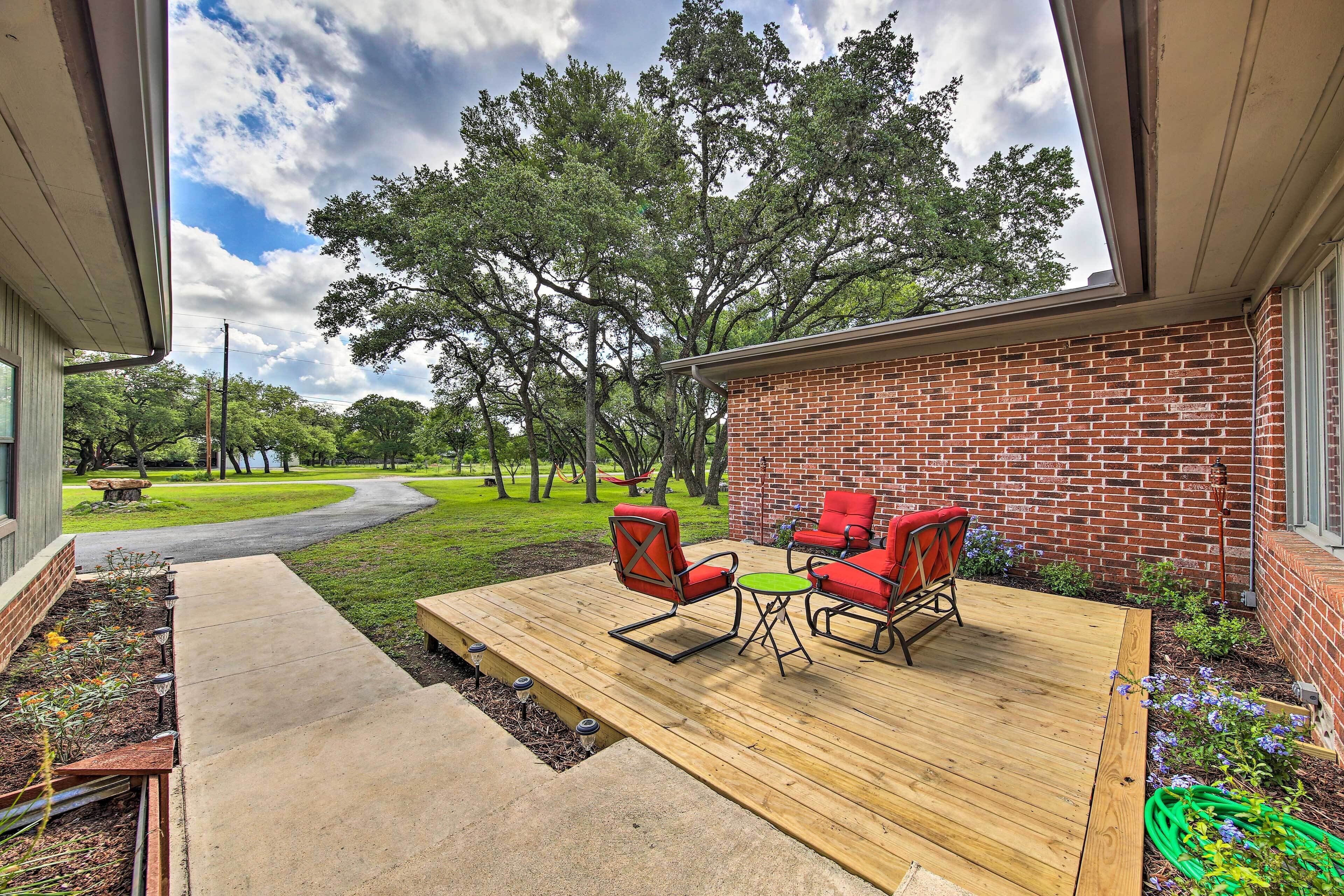 A patio with outdoor furniture, a brick wall, and a view of a lawn and trees.