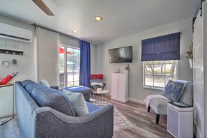 A modern living room with a grey sofa, a small round table, a white cabinet, and a TV mounted on the wall. - Family Friendly Hill Country Home: 13 Mi to Lake! (New Braunfels)
