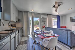 A modern kitchen with white cabinets, a dining area with a red table, and a blue sofa. - Family Friendly Hill Country Home: 13 Mi to Lake! (New Braunfels)