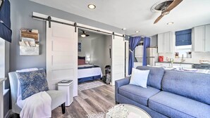 Una habitación de hotel moderna con sofá, una silla, una mesita y una kitchenette.