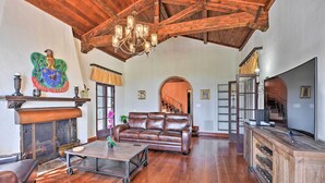 A spacious living room with a wooden ceiling, leather sofa, and a fireplace.