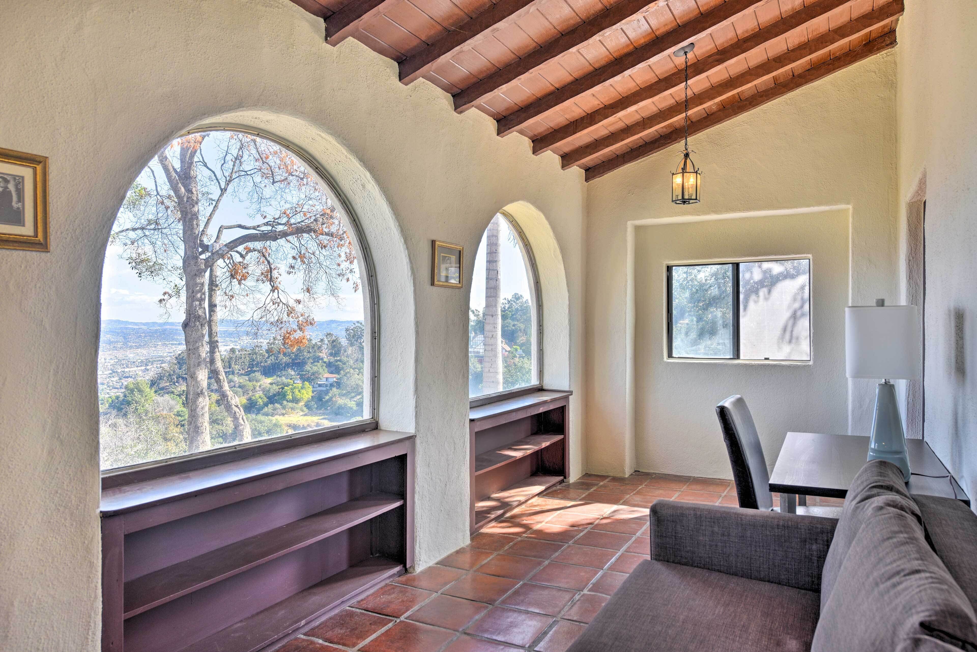 A cozy room with a view of trees and hills, a wooden ceiling, and a built-in bench.