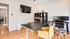 A modern living room with a dining table, chairs, a bookshelf, a television, and a ceiling fan. - Updated Baltimore Home 8 Mi to Downtown! (Baltimore)