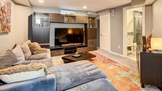 A modern living room with a flat-screen TV, grey sofas, a coffee table, and a colorful rug. - Updated Baltimore Home 8 Mi to Downtown! (Baltimore)