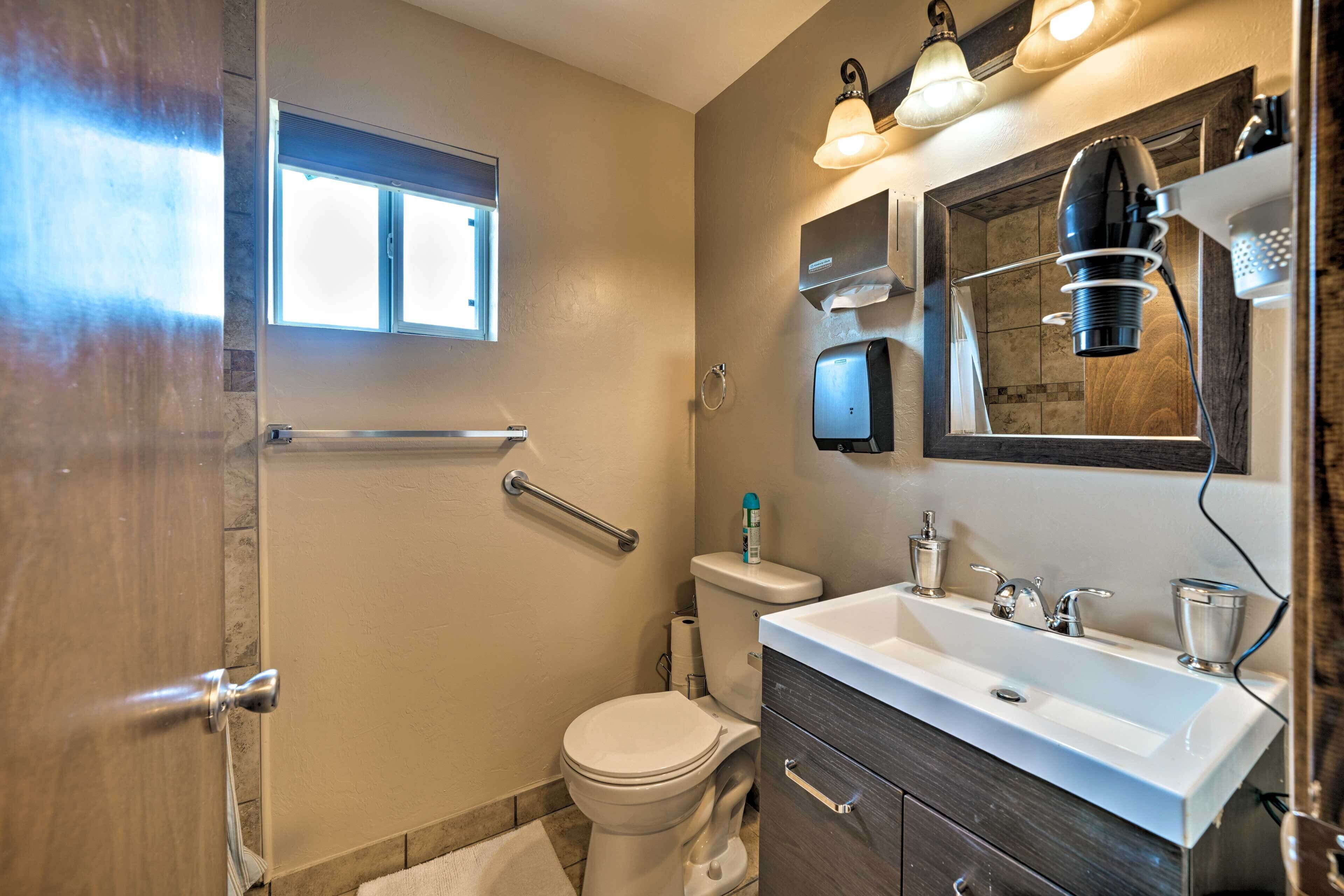 A bathroom with a toilet, sink, vanity, and a window.