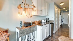 A modern kitchen with white cabinets, a granite countertop, and a unique rope chandelier. - Family Beach Retreat w/ Pool & Views in Galveston (Galveston)