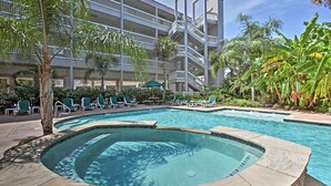 A hotel pool area with a hot tub, lounge chairs, and palm trees. - Family Beach Retreat w/ Pool & Views in Galveston (Galveston)