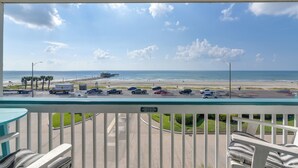 A balcony with a view of the beach, parked cars, and a pier in the distance. - Family Beach Retreat w/ Pool & Views in Galveston (Galveston)