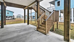 A covered outdoor area with a wooden staircase leading to a second-floor balcony.