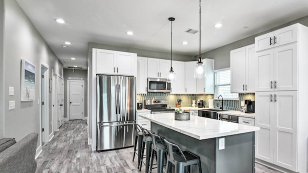 A modern kitchen with white cabinets, stainless steel appliances, and a central island with bar stools.