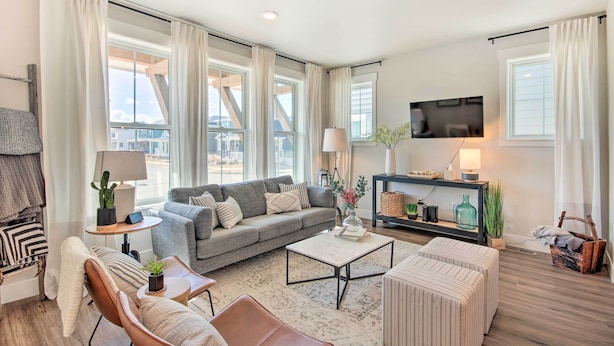 A modern living room with a grey sofa, a coffee table, and a TV mounted on the wall. - Walk to Parks! Billings Gem w/ Soaking Tub (Billings)
