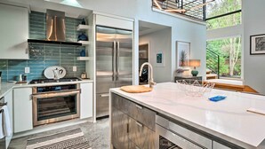 Une cuisine moderne dotée d’appareils électroménagers en acier inoxydable, d’un grand îlot central et offrant une vue sur l’extérieur.