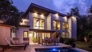Une maison moderne à deux étages, dotée d’une piscine, d’un espace salon extérieur et d’un escalier menant à l’étage supérieur.