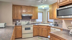 A kitchen with wooden cabinets, a stainless steel microwave, a stove, and a dishwasher. - Eagan Home w/ Porch - 5 Mi to Mall of America! (Eagan)