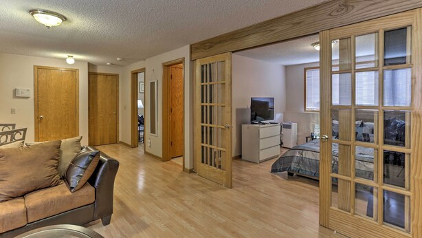 A spacious living room with a sofa, a television, and a bed with patterned bedding. - Eagan Home w/ Porch - 5 Mi to Mall of America! (Eagan)