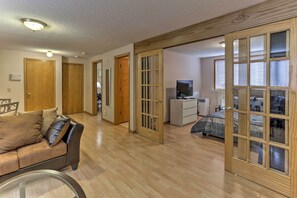 A spacious living room with a sofa, a television, and a bed with patterned bedding. - Eagan Home w/ Porch - 5 Mi to Mall of America! (Eagan)