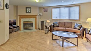 A living room with a fireplace, a sofa, a coffee table, and a television. - Eagan Home w/ Porch - 5 Mi to Mall of America! (Eagan)