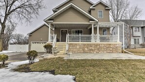 A two-story house with a front porch, a garage, and a stone foundation. - Eagan Home w/ Porch - 5 Mi to Mall of America! (Eagan)