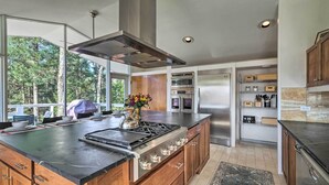 Una cocina moderna con una isla grande, electrodomésticos de acero inoxidable y vistas al exterior.
