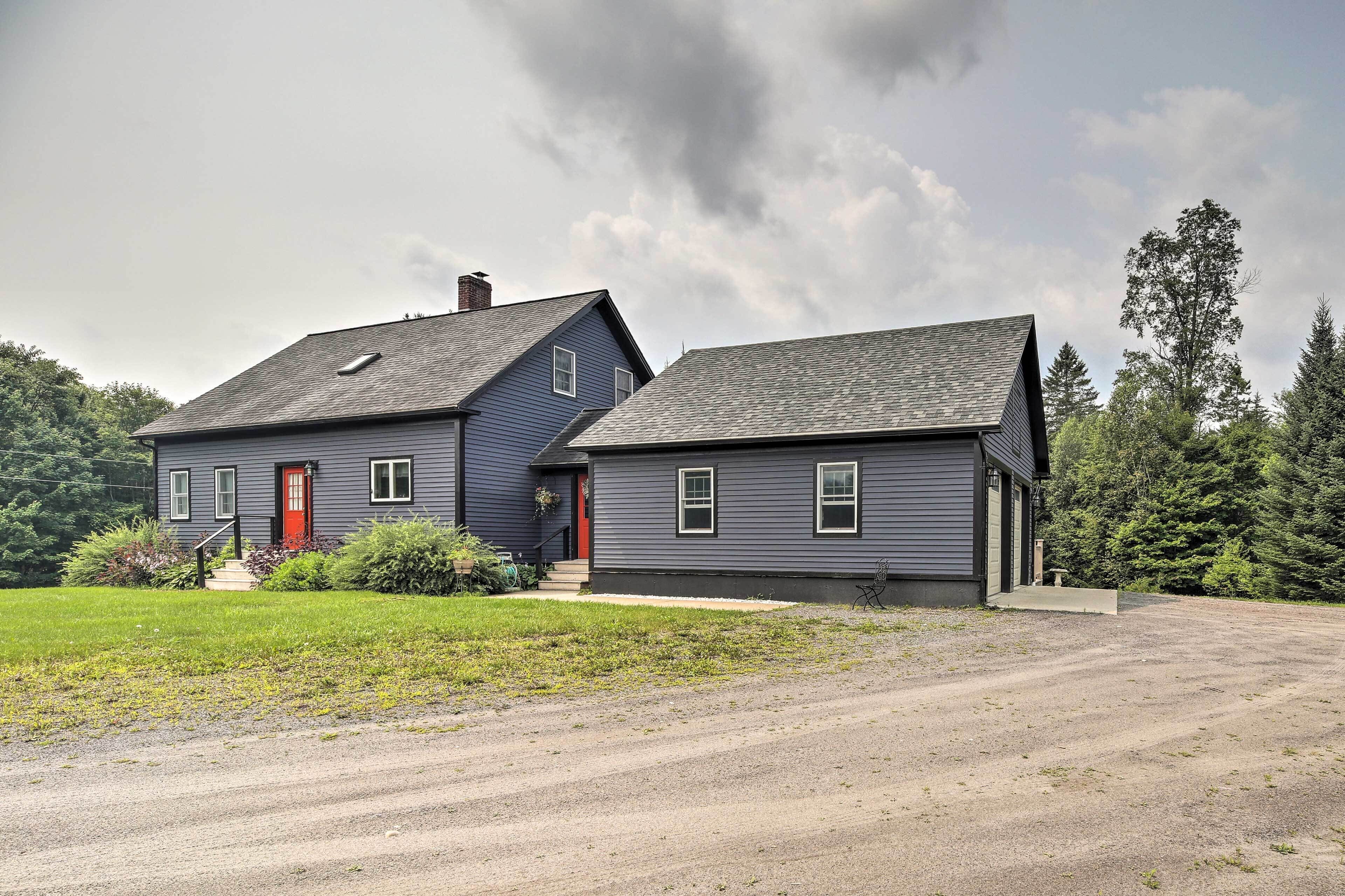 A two-story house with a red door and a grey exterior.