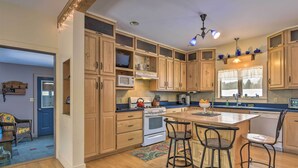 Une cuisine avec des meubles de rangement en bois, une cuisinière et des tabourets de bar.