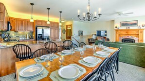 A spacious kitchen with wooden cabinets, a large island, and a dining area set for six with a long wooden table and six chairs. - Inviting Ski-in/ski-out Condo at Jay Peak Resort! (North Troy)
