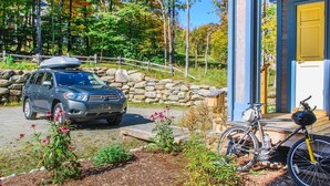 A car parked in front of a house with a stone wall and a wooden deck. - Inviting Ski-in/ski-out Condo at Jay Peak Resort! (North Troy)