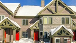 A row of two-story houses with steeply pitched roofs, red doors, and a 'No Parking' sign visible. - Inviting Ski-in/ski-out Condo at Jay Peak Resort! (North Troy)
