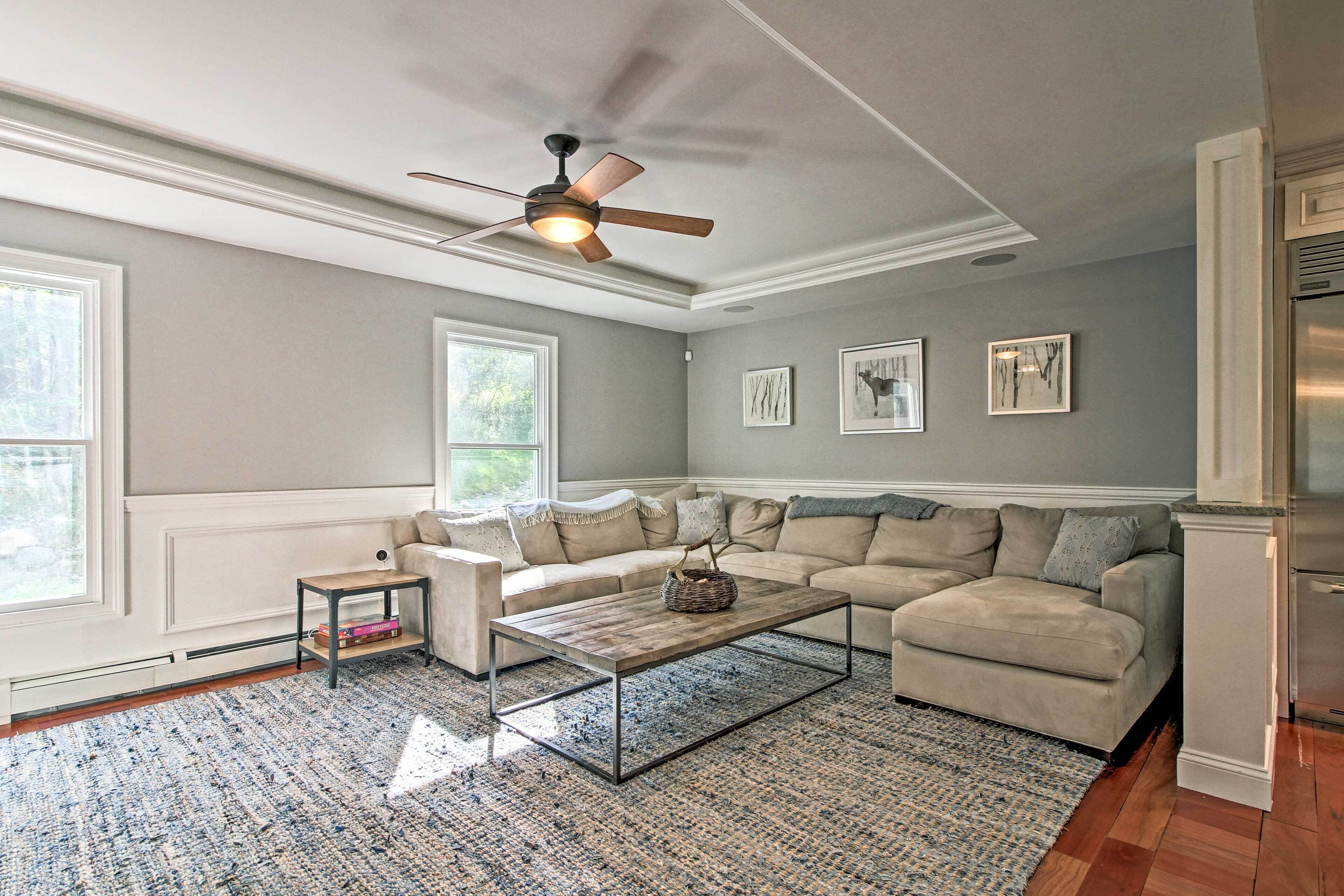 A living room with a sectional sofa, a coffee table, a ceiling fan, and a large window.