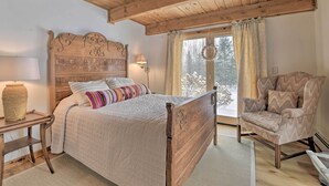 A bedroom with a wooden bed, a chair, a lamp, and a window with curtains.