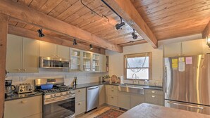 A modern kitchen with wooden beams, stainless steel appliances, and white cabinets.