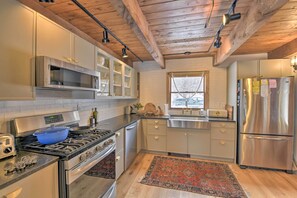 Una cucina moderna con elettrodomestici in acciaio inossidabile, travi in legno a soffitto e una finestra vista alberi.