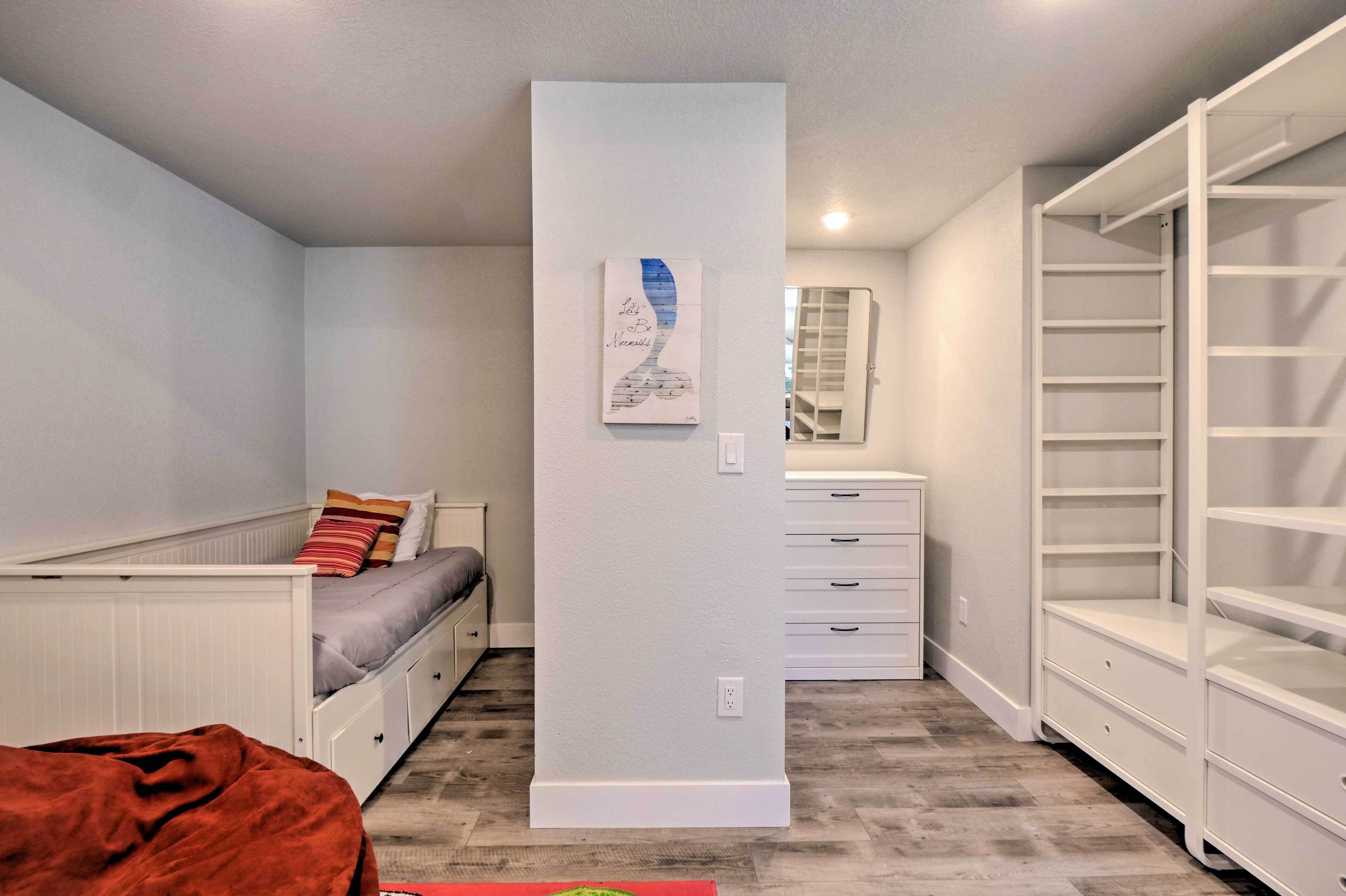 A bedroom with a bed, a nightstand, a dresser, and a walk-in closet.