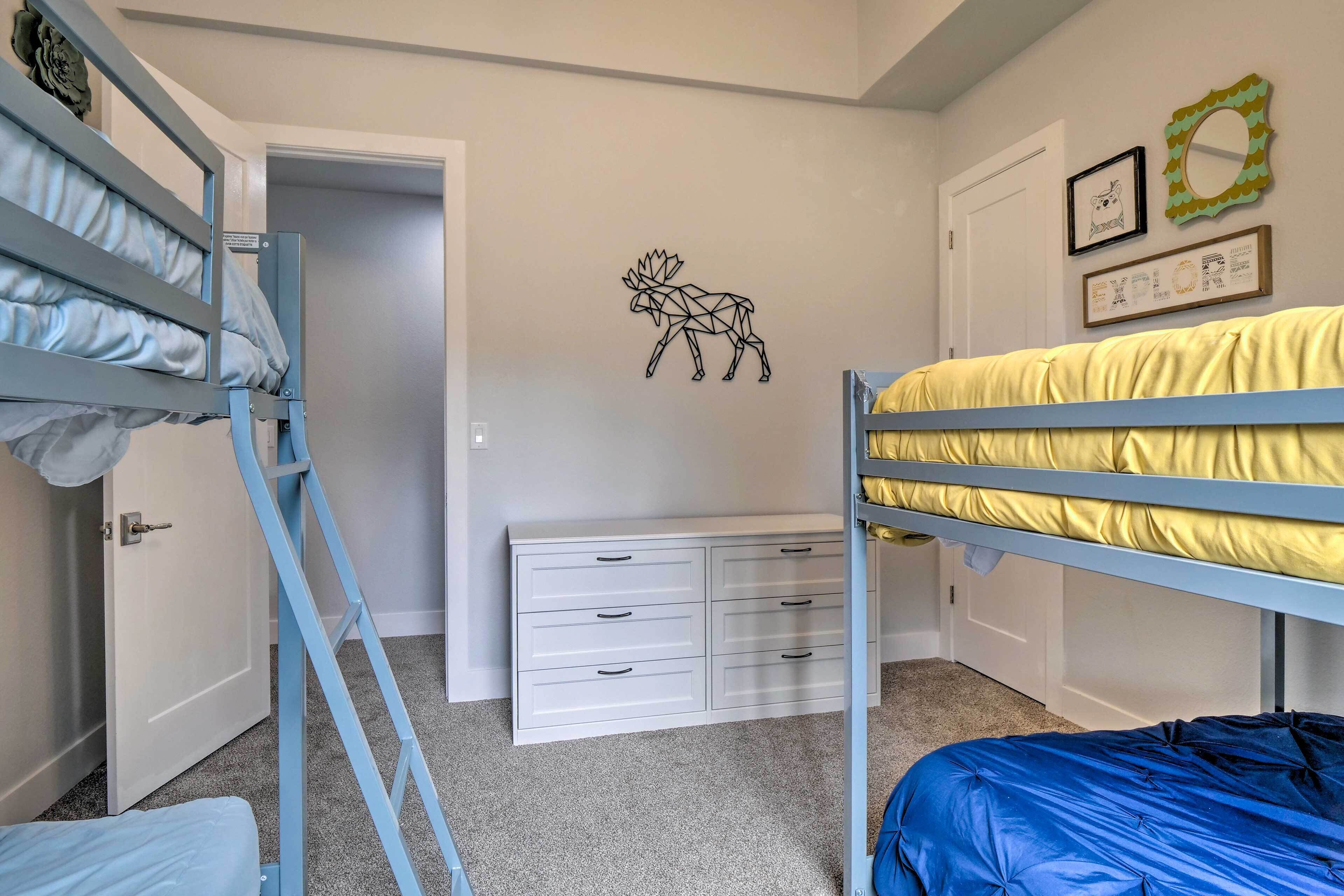 A bedroom with bunk beds, a white dresser, and wall decorations including a moose and framed items.