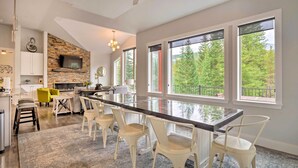 A modern kitchen with a stone backsplash, large windows, and a bar area with white chairs. - 3 Mi to Ski Resort: Hot Tub Haven in Breckenridge! (Breckenridge)