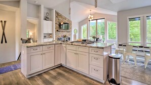 A modern kitchen with white cabinets, a stone backsplash, and a large window overlooking greenery. - 3 Mi to Ski Resort: Hot Tub Haven in Breckenridge! (Breckenridge)