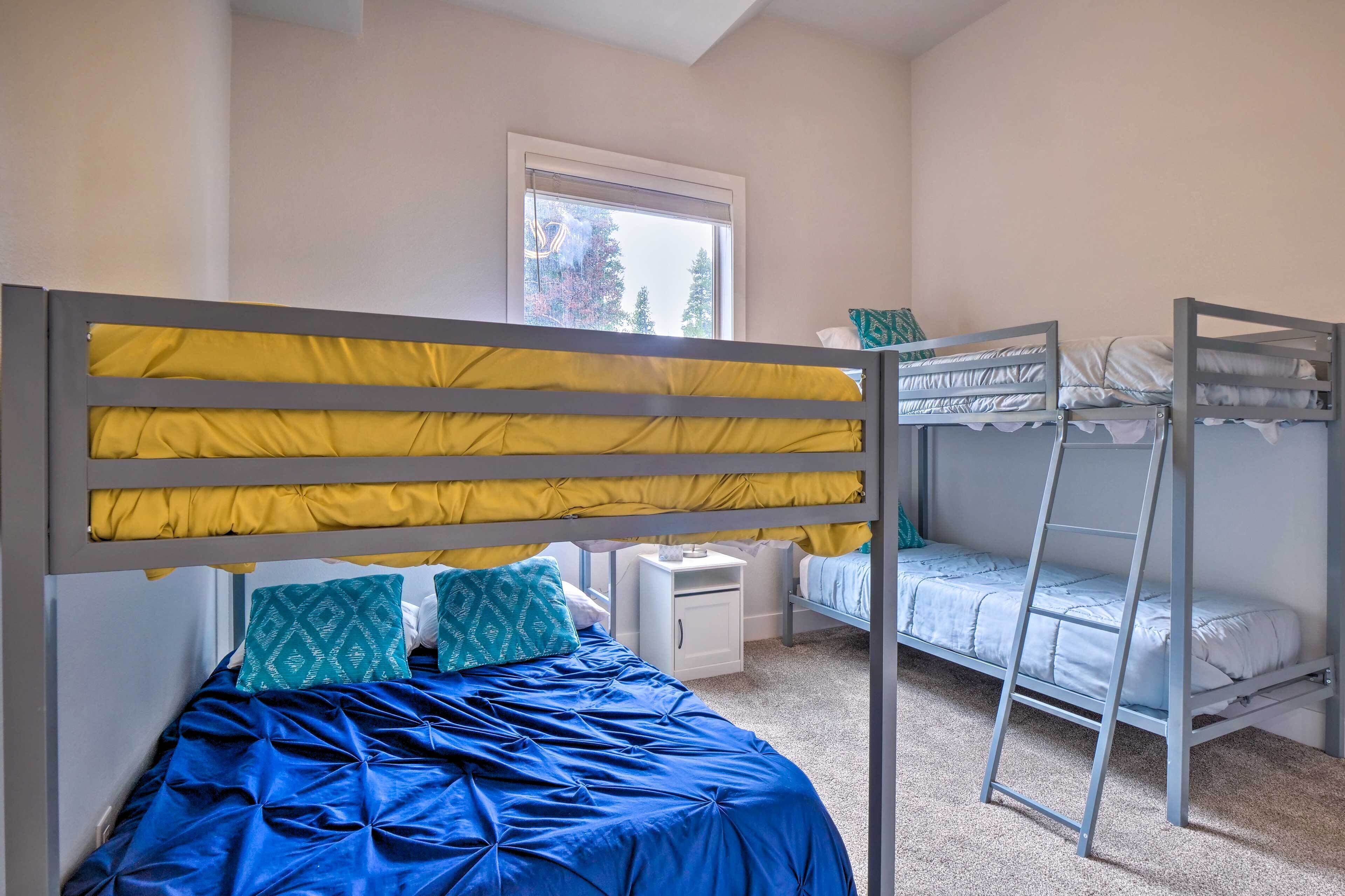 A bedroom with a bunk bed, a single bed, a nightstand, and a window.