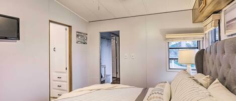 Ein Schlafzimmer mit einem Bett, einem Deckenventilator, einem Fenster mit Aussicht und einer Tür zu einem anderen Raum.